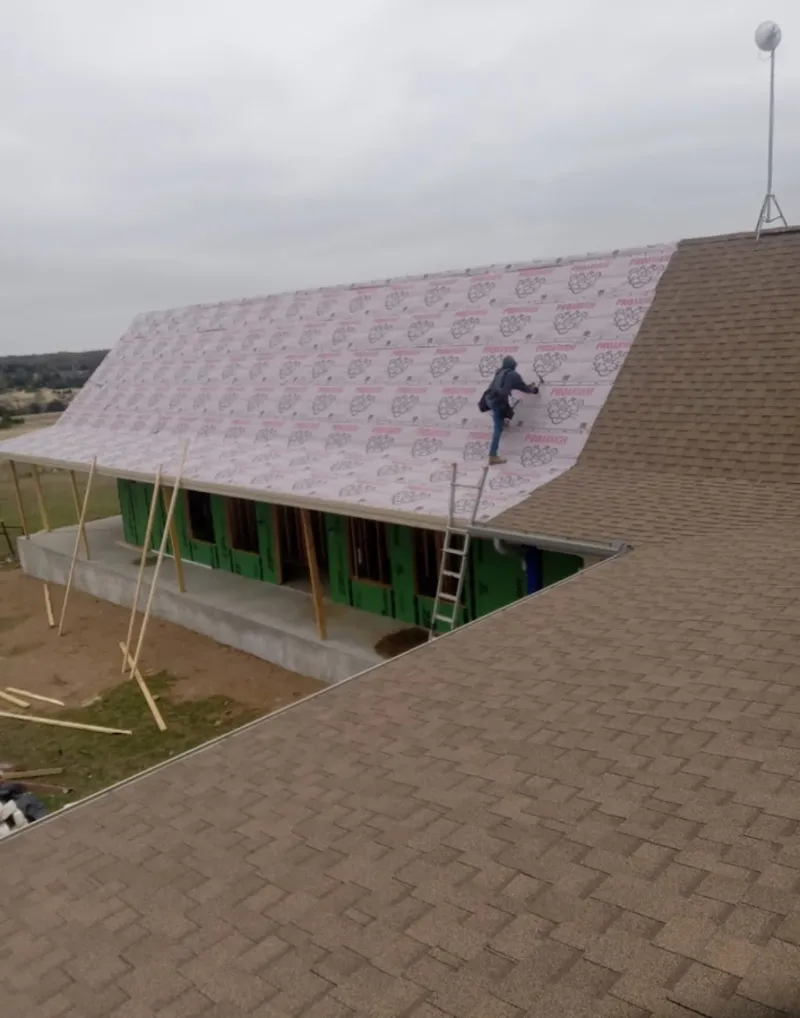 Worker preparing underlayment for a metal roof installation in White Oak